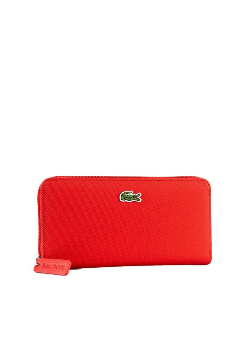 Portefeuille zippé rouge en matière texturée, avec un logo crocodile Lacoste vert et une petite étiquette de marque.