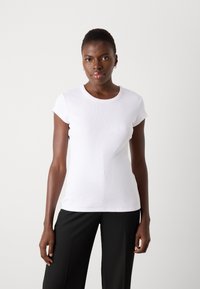 T-shirt blanc à manches courtes avec un col rond et une texture côtelée. Design simple sans motifs ni accents notables.