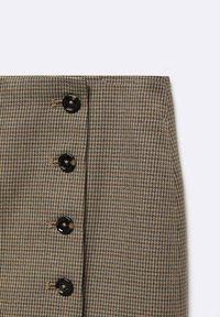 Ruskean houndstooth-kuosisukka, jossa on suuret mustat napit, ominaisena teksturoitu kangas ja suora leikkaus.