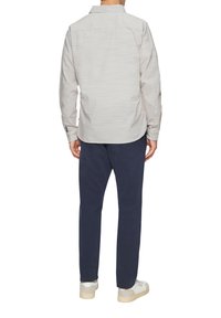 Lichtgrijs textuur langemouwen shirt met een puntige kraag, knoopmanchetten, gecombineerd met marineblauwe broek en witte sneakers.