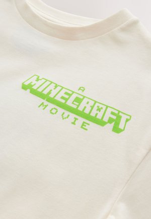 Vit bomullst-shirt med en klargrön pixelgrafik som lyder "A MINECRAFT MOVIE", rund halsringning och korta ärmar.