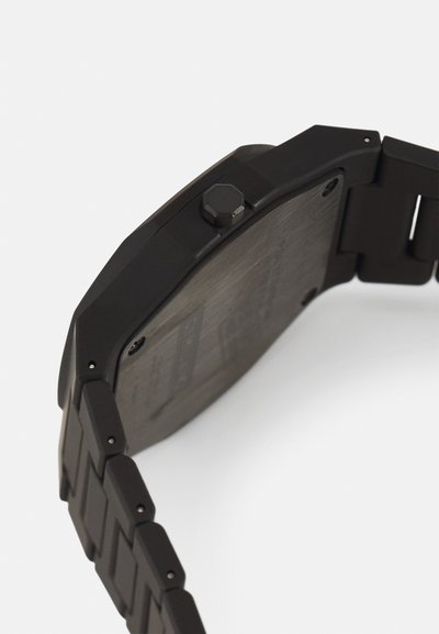 Zwart metalen horloge met een octagonale kast, een gestructureerd oppervlak en een hexagonale kroon. De band heeft rechthoekige schakels.