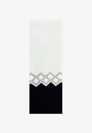 Maglione lavorato a maglia con una parte superiore bianca caratterizzata da un motivo in pizzo geometrico e una parte inferiore nera solida. Tessuto con texture in tutto il capo.