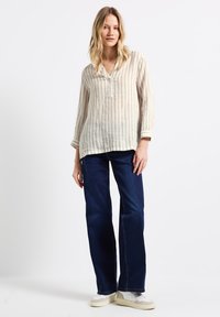 Randig linne skjorta med V-ringning och långa ärmar, i kombination med mörkblå vida jeans och ljusa sneakers.