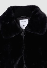 Giacca in pelliccia sintetica nera con colletto arrotondato, chiusura a zip e un'etichetta con la scritta "TERRANOVA" taglia "S". La texture appare morbida e pelosa.