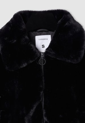 Giacca in pelliccia sintetica nera con colletto arrotondato, chiusura a zip e un'etichetta con la scritta "TERRANOVA" taglia "S". La texture appare morbida e pelosa.