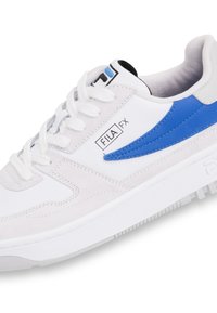 Baskets blanches avec un accent en cuir bleu, en daim et en matériaux synthétiques, à bout rond et à lacets. Style athlétique avec des détails texturés.