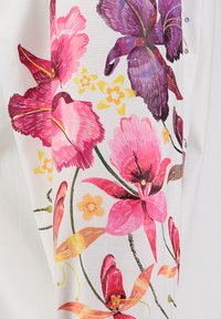 Patrón floral brillante con flores rosas, moradas, naranjas y amarillas y tallos verdes sobre un fondo de tela blanca.