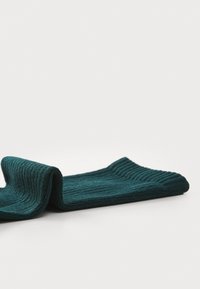 Teal ribbet sokk laget av mykt strikket materiale, med en brettbar mansjett og en teksturert overflate for økt grep og komfort.