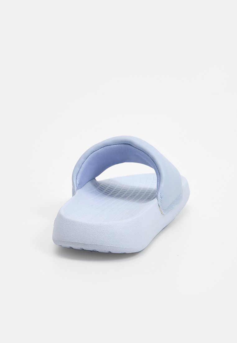 Sandale à glissière bleu clair avec une large sangle unique, semelle en caoutchouc solide et semelle intérieure texturée. Matériau doux et design minimaliste.