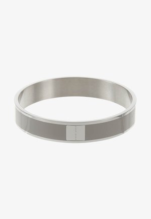 Alianza de boda de metal plateado sencillo con una superficie lisa, ligeramente redondeada y un pequeño detalle rectangular en el lado exterior.