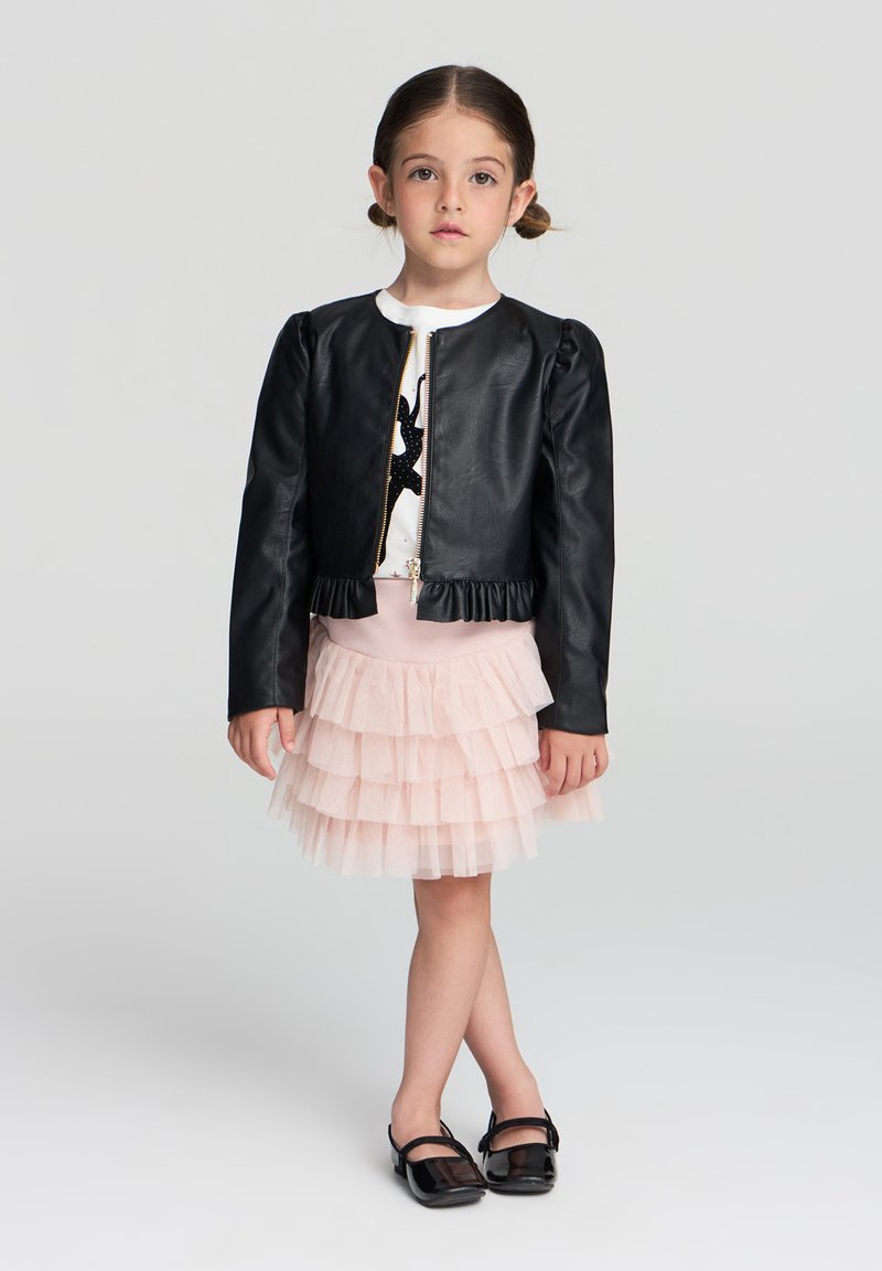 Giacca nera in ecopelle con zip frontale, orlo a coste e maniche a sbuffo, abbinata a una gonna in tulle rosa a strati e scarpe nere.