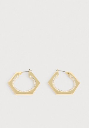 Arany hatszög alakú karika fülbevalók sima felülettel és egy sor tiszta kristállyal a belső él mentén. Fém kiegészítők egészítik ki a dizájnt.