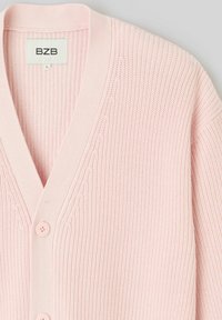 Cardigan en tricot rose clair avec un col en V, présentant un motif texturé, cinq boutons à l'avant et des bordures côtelées. L'étiquette indique "BZB."