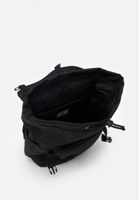 Mochila negra con un exterior de tela suave, cierre de cordón, correas ajustables y forro interior liso que incluye un bolsillo.