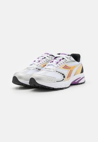 Scarpe sportive bianche con tomaia in mesh, dettagli viola e strisce gialle. Presentano un collare imbottito e una suola in gomma nera testurizzata.