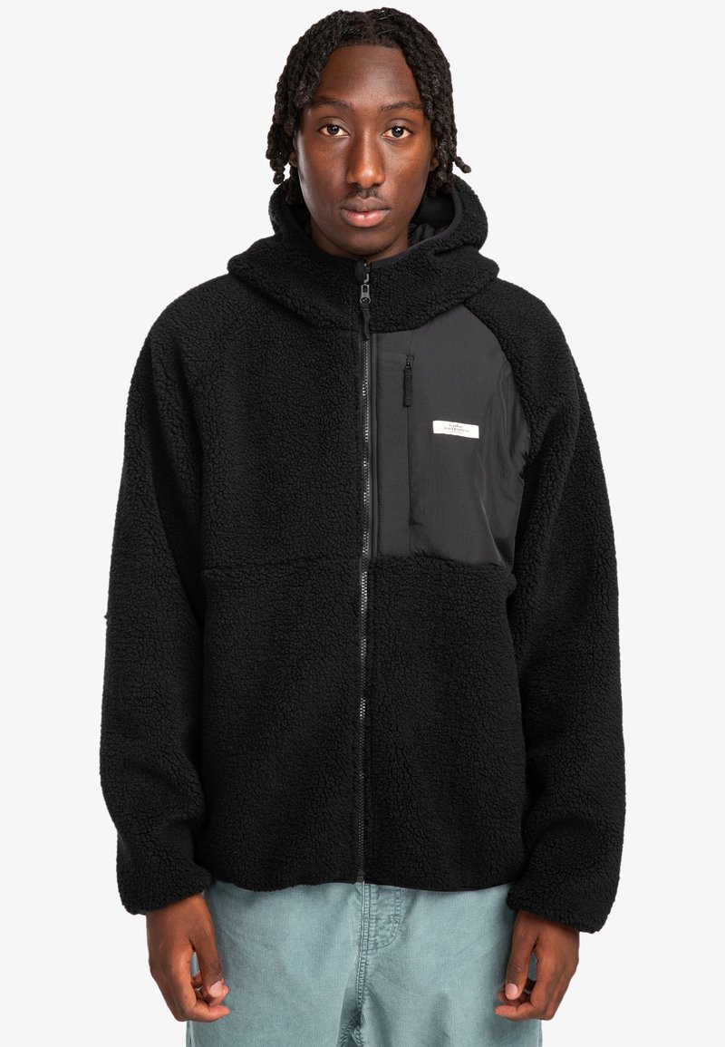 Sudadera de forro polar negra con cremallera frontal, tejido texturizado, bolsillo tipo canguro y un bolsillo en el pecho en contraste con una etiqueta.