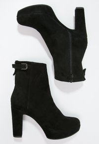 Black suede ankle boots with a chunky heel, zip closure, and a buckle accent. Features a rounded toe and smooth texture.