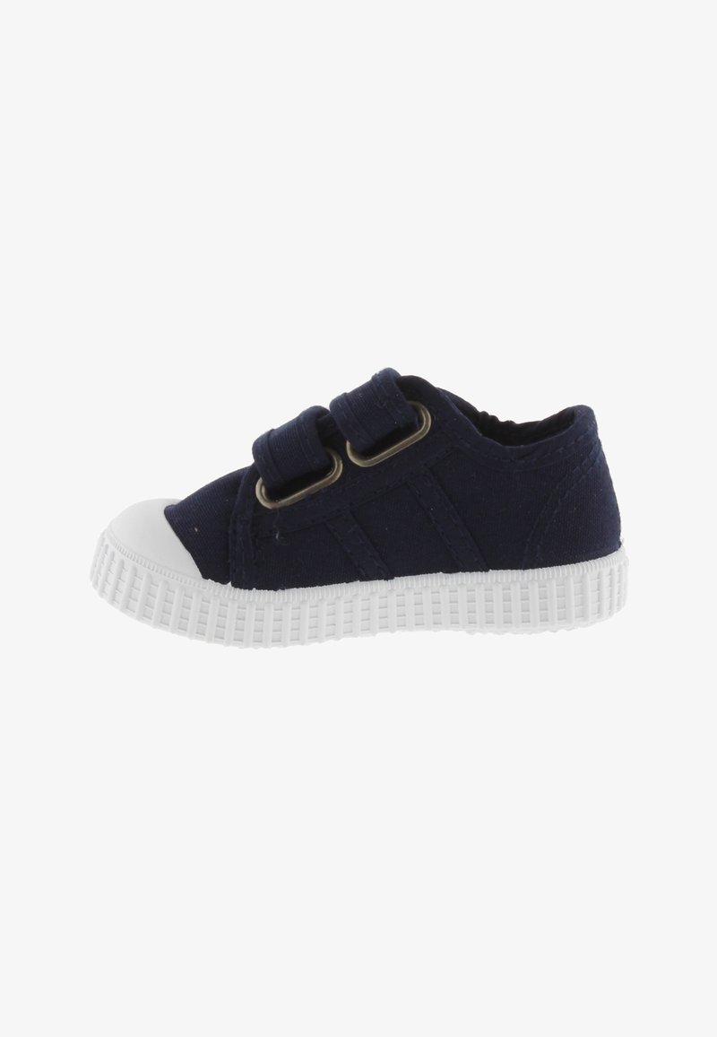Sneaker per bambini in tela blu navy con due cinturini regolabili, punta in gomma bianca e suola testurizzata bianca. Design standard a bassa altezza.
