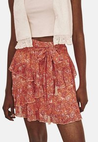 Falda de estampado paisley naranja con capas con volantes, cinturón atado en la cintura y acentos de borlas. Hecha de tela ligera.