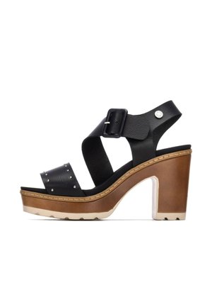 Sandalias de plataforma de cuero negro con una amplia tira cruzada y cierre de hebilla, acentuadas con tachuelas plateadas, con un tacón bloque marrón.