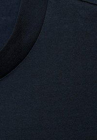 Námořnická modrá látka s žebrovanou strukturou, s kulatým výstřihem a hladkým, jemným povrchem. Obraz zdůrazňuje detaily látky.