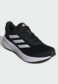 Schwarzer Sportschuh mit atmungsaktivem Mesh-Obermaterial, weißen Streifenakzenten und strukturiertem Gummisohle. Verfügt über Schnürsenkel und gepolsterten Kragen für Komfort.