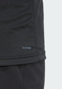 Sort atletisk skjorte med struktureret design, fugttransporterende stof og et lille "CLIMACOOL" mærkat nær kanten.