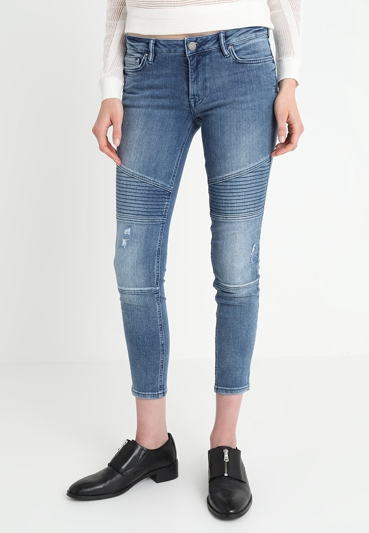 Jeans de mezclilla azul con un ajuste slim, que presentan paneles acanalados a lo largo de las piernas y acentos desgastados. Largo recortado y cintura de media altura.