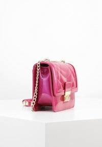 Różowa torebka crossbody z lakierowanej skóry, z pikowanym wzorem, złotymi akcentami i łańcuszkowym paskiem. Kompaktowy prostokątny kształt z przednią klapą.