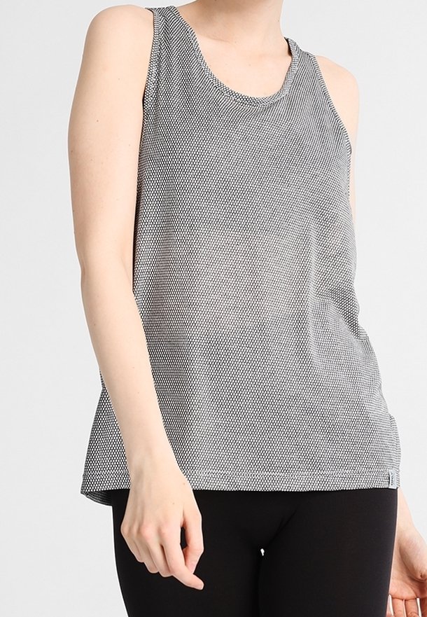 Débardeur sans manches noir et blanc avec un motif à pois, un col rond et une coupe ample. Tissu doux avec une texture lisse.