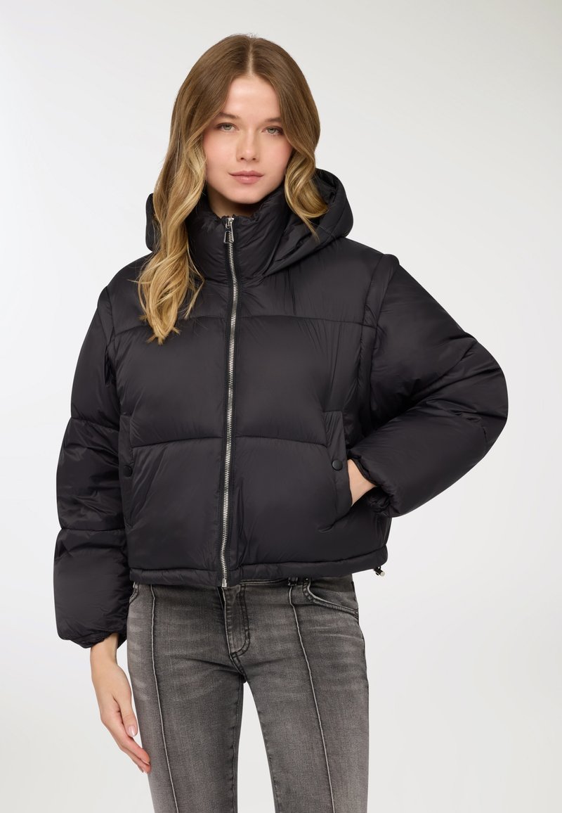 Giacca a vento nera imbottita con cappuccio, dotata di chiusura frontale con zip, tasche con zip e design corto. Materiale liscio e lucido con una leggera brillantezza.