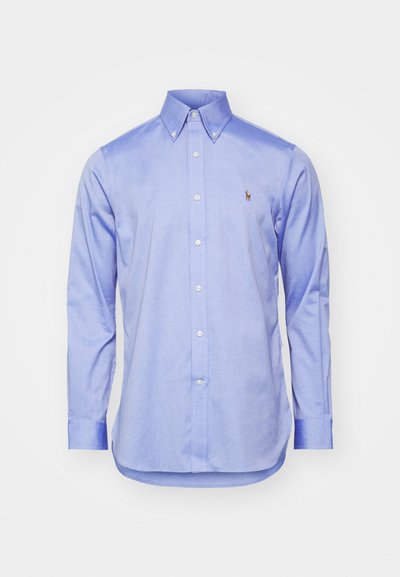 Camisa de botão azul clarinho em tecido de algodão, com colarinho pontudo, mangas longas e um pequeno logotipo no lado esquerdo do peito.