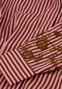Bruin en roze gestreepte stof met bloemendisign op de manchetten, met een soepele textuur en intricaties.
