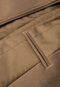 Brauner Stoff mit glatter Textur, ausgestattet mit einer Reißverschlusstasche und kontrastierendem gemustertem Material entlang des Randes.
