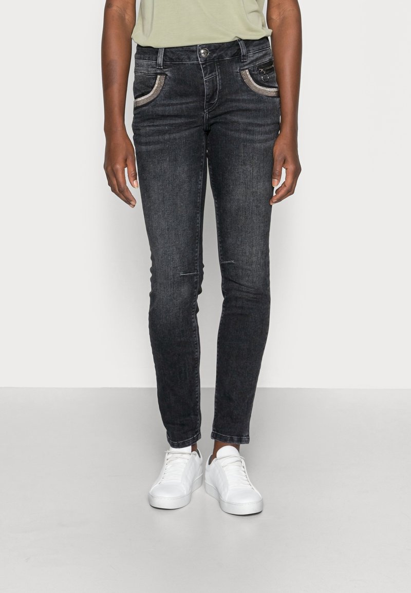 Tunna svarta denimjeans med kontrasterande fickdetaljer, fem fickor, lätt slitningar på knäna och silverfärgad hårdvara.