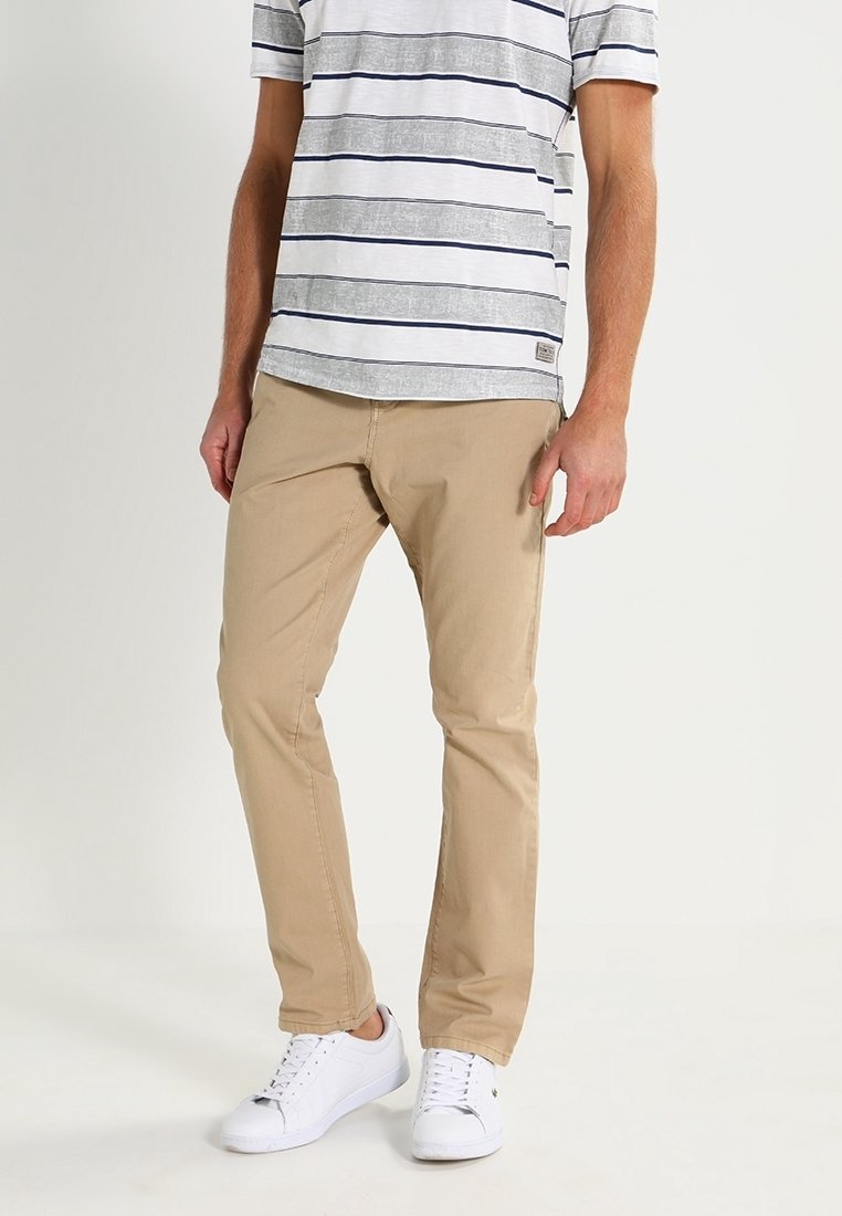 Beige chinos, triko s šedými a bílými pruhy a bílé tenisky. Bavlněný materiál, volný střih a krátké rukávy s detailním štítkem.