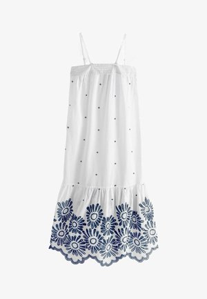 Bela bomba iz bombaža s tankimi naraminicami, okrašena z modrimi vezenimi cvetličnimi vzorci in detajli z očesci ob robu. Oblika z razširjenim dnom.