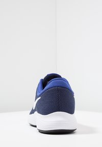 Zapatilla deportiva azul marino con parte superior de malla, entresuela blanca y parte trasera texturizada. Cuenta con un cuello acolchado y detalle del logo en blanco en contraste.
