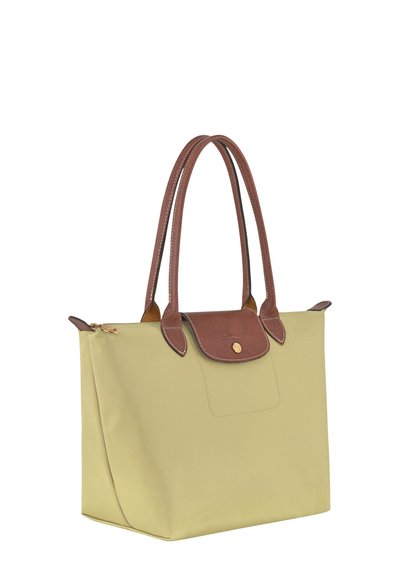 Tote bag in light green material with brown leather accents and handles, featuring a front pocket and gold-tone snap closure.