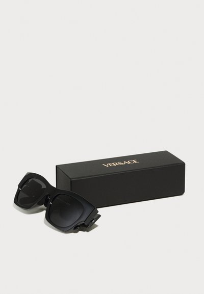 Mustad mustadprillid tumedate läätsedega, millel on tukk ja ruudukujuline disain. Kaasas must kast kullavärvi "Versace" logoga.
