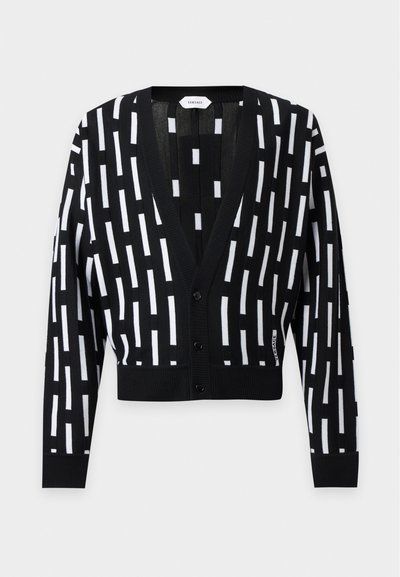 Cardigan noir avec motifs rectangulaires verticaux blancs, manches longues, fermeture à boutons sur le devant, coupe courte et étiquette Versace sur le côté.