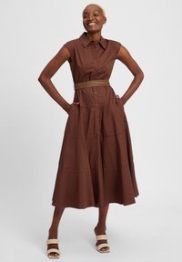 Brown, sleeveless dress with a button front, flared hem, and pockets; features a braided belt at the waist and smooth, textured fabric.