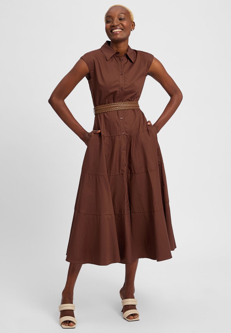 Brown, sleeveless dress with a button front, flared hem, and pockets; features a braided belt at the waist and smooth, textured fabric.