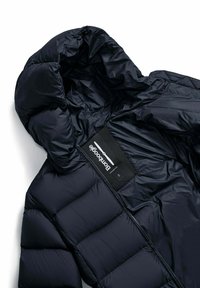Giacca a vento blu navy con cappuccio, caratterizzata da sezioni trapuntate, una trama esterna liscia e un'etichetta che indica il marchio "bomboogale."