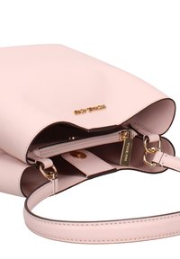 Sac à main en cuir rose texturé avec un logo doré, une poche zippée et une bandoulière ajustable. Présente un design épuré et minimaliste.