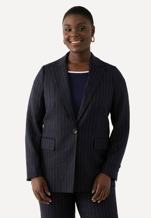 Námořnický blazer s pruhy, s klopovými límci, jedním knoflíkem a dvěma předními kapsami. Hladká textura, přiléhavý střih a strukturovaný design.