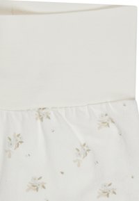 Weißer Stoff mit einem beigen elastischen Bund und einem dezenten Muster aus kleinen beigen und hellbraunen Blumenprints.