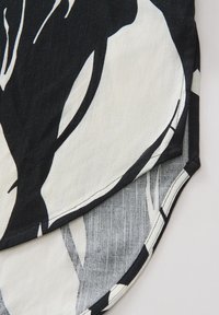 Tessuto astratto in bianco e nero con una trama testurizzata, dotato di un orlo curvo e di un bordo nero a contrasto lungo i lati.