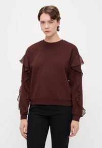 Sweatshirt borgonha com mangas longas, apresentando detalhes em renda transparente e decote redondo. Tecido suave e texturizado com bainha ajustada.